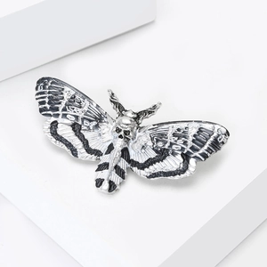 Macro detail of gothic death's-head hawkmoth brooch with silver and black enamel