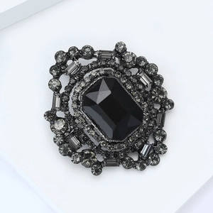 Détail d'une broche vintage avec une grande pierre noire octogonale et cristaux gris