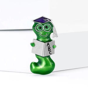 Macro detail of enamel bookworm brooch with purple graduation cap and ABC book