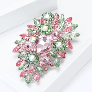 Gros plan d'une broche fleurie en cristal rose et vert avec pierres facettées