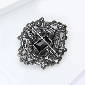 Détail macro du dos d'une broche avec fermoir sécurisé et pierre précieuse noire facettée