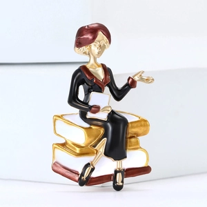 Detail of elegant teacher brooch with red beret on books, gold-plated enamel craft
