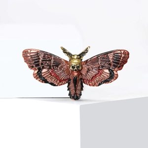 Gothic moth brooch with red enamel and golden skull on geometric white display