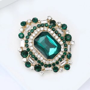 Détail d'une broche de luxe avec strass vert taille émeraude et cristaux sur métal doré