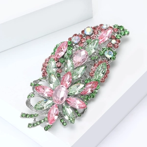 Vue latérale macro d'une broche fleurie en cristal avec pierres roses et vertes sur support