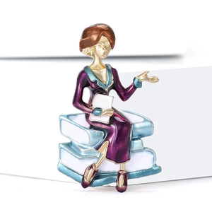 Detail of female teacher brooch featuring enamel finish on books with a purple dress