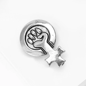 Détail d'un badge féministe vintage en argent avec poing serré et symbole vénus