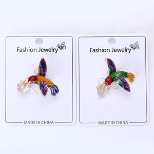 Détail de broches colibris en émail avec ailes violettes et motifs floraux