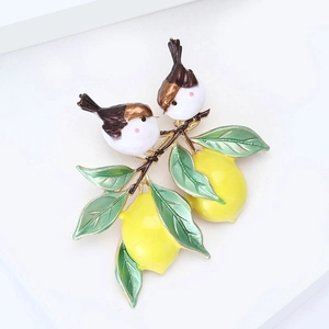 Détail d'une broche branche de citron en émail avec deux oiseaux et fruits jaunes vifs