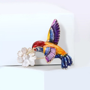 Broche colibri en émail vibrant avec fleur argentée sur support géométrique blanc