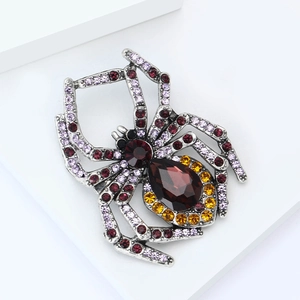 Makroaufnahme der Vintage-Spinne-Brosche mit tiefrotem birnenförmigem Stein und Kristallbesatz