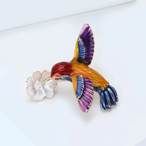 Gros plan détaillé d'une broche colibri en émail coloré avec une petite fleur
