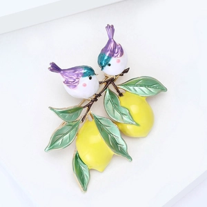 Vue détaillée d'une broche en émail coloré avec des oiseaux sur une branche de citron
