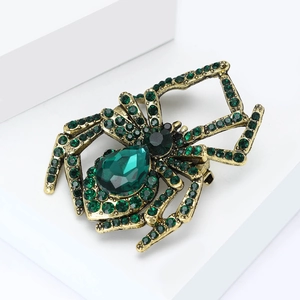 Detailed view of vintage gold spider brooch with green teardrop crystal and rhinestones