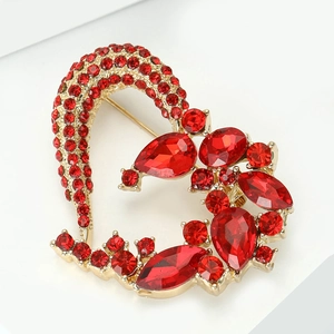 Close-up of heart-shaped gold brooch with sparkling red rhinestones and crystals