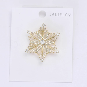 Detail of a golden snowflake brooch with sparkling zircons on white jewelry card