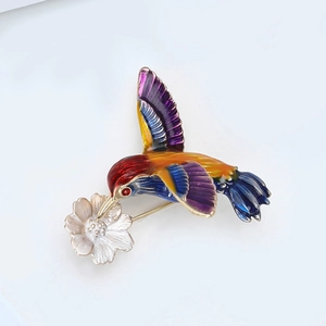 Détail de la broche colibri en émail avec fleur argentée et pierre rouge