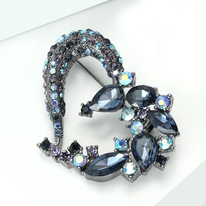 Detail of heart-shaped brooch featuring dark metal plating and multi-color rhinestones