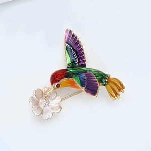 Détail de la broche colibri colorée avec émail et accent floral plaqué or brillant