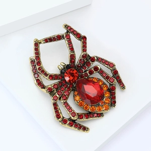 Nahaufnahme der Vintage-Spinne-Brosche mit roten Kristallen und goldener Basis auf Weiß