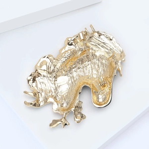 Close-up of the golden metal back of the horse brooch showing texture and safety pin