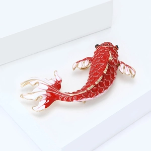 Macro detail of red enamel koi fish brooch with golden scales and red stone inlay