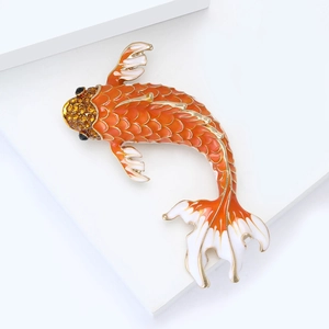 Macro detail of koi fish brooch featuring orange enamel scales and amber rhinestones