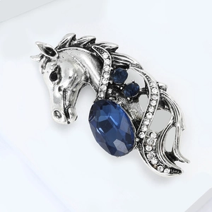 Macro view of vintage silver horse brooch with deep blue crystal and white rhinestones