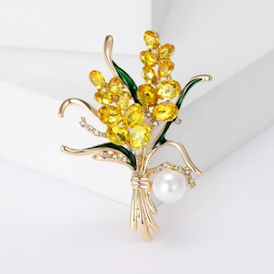 Détail d'une broche épi de blé dorée avec cristaux jaunes, émail vert et une grande perle