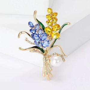 Détail d'une broche en alliage doré ornée de gemmes colorées et d'une grande perle