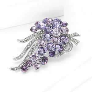 Macro shot of silver brooch featuring faceted purple crystals and white rhinestones