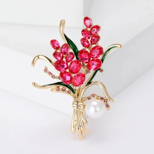 Détails d'une broche en forme de blé avec cristaux rouges, émail vert et perle blanche