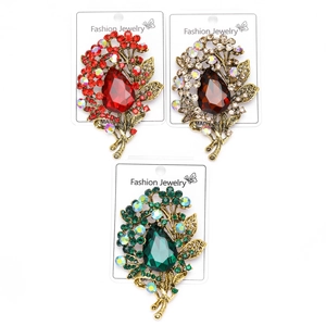 Macro detail of vintage crystal brooches with teardrop stones in red, brown, and green