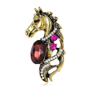 Vintage horse head brooch in gold metal with large reddish-brown gemstone and white diamonds