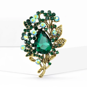 Detailed macro view of vintage gold flower brooch with large green teardrop crystal