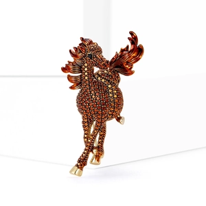 Detailed macro view of the sparkling orange rhinestones and red enamel wings on the pegasus brooch