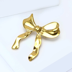 Détail macro d'une broche nœud dorée avec texture martelée sur un bloc géométrique