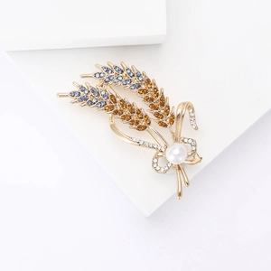 Detail of wheat ear brooch with blue rhinestones, gold plating, and a white pearl accent