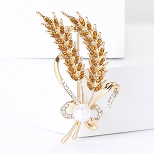 Macro detail of alloy wheat brooch with amber crystals and elegant white pearl