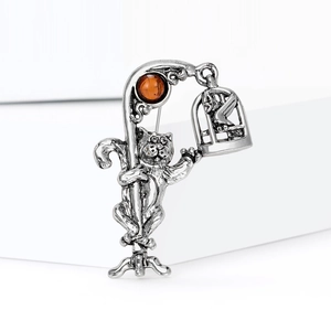 Macro detail of vintage silver cat brooch with amber gemstone and ornate street lamp