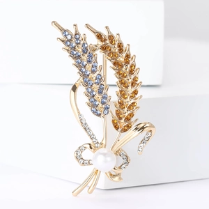 Elegant wheat stalk brooch with blue and amber crystals, pearl and ribbon on white stand