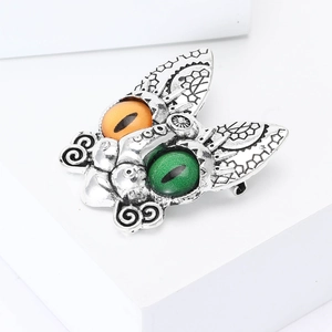 Macro detail of vintage silver moth brooch with mystical amber and emerald eye gemstones