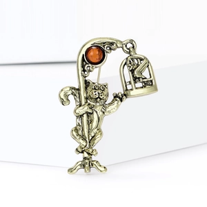Detailed view of antique gold cat brooch with vintage street lamp and hollow birdcage