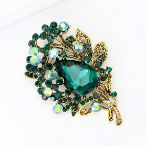 Detail of vintage gold brooch with large emerald green drop crystal and AB rhinestones