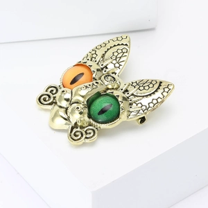 Detailed view of a vintage insect moth brooch with large amber and green gem eyes