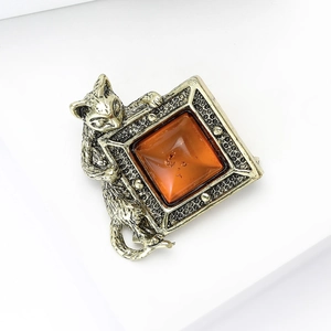Détail d'une broche chat vintage avec pierre ambre carrée sur un support d'exposition