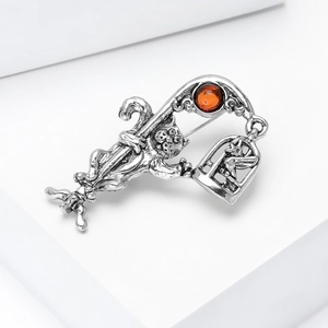 Detail of vintage silver cat brooch with umbrella and birdcage on a white stand