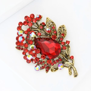 Detailed view of vintage gold brooch with large red teardrop crystal and colorful rhinestones