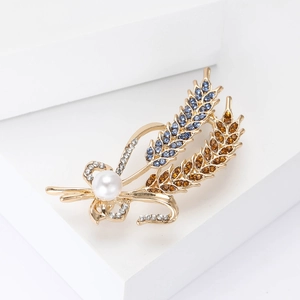 Macro detail of elegant wheat brooch with blue rhinestones and a white pearl on a gold base
