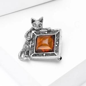 Détail macro d'une broche chat argentée avec une pierre ambre carrée et métal de style rétro
